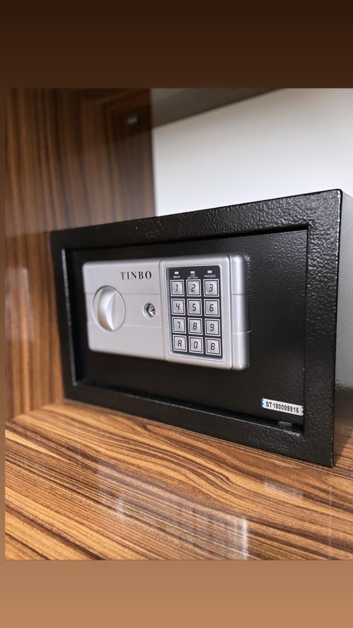 A secure, metallic, keypad entry system labeled "TINBO" with a numeric keypad and a lock button, mounted on a wooden surface.