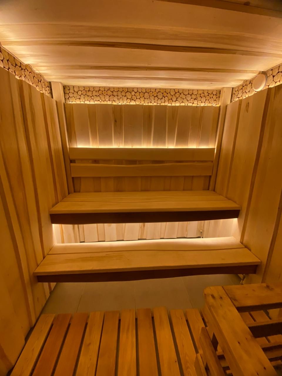 A sauna with wooden benches and a stone wall.