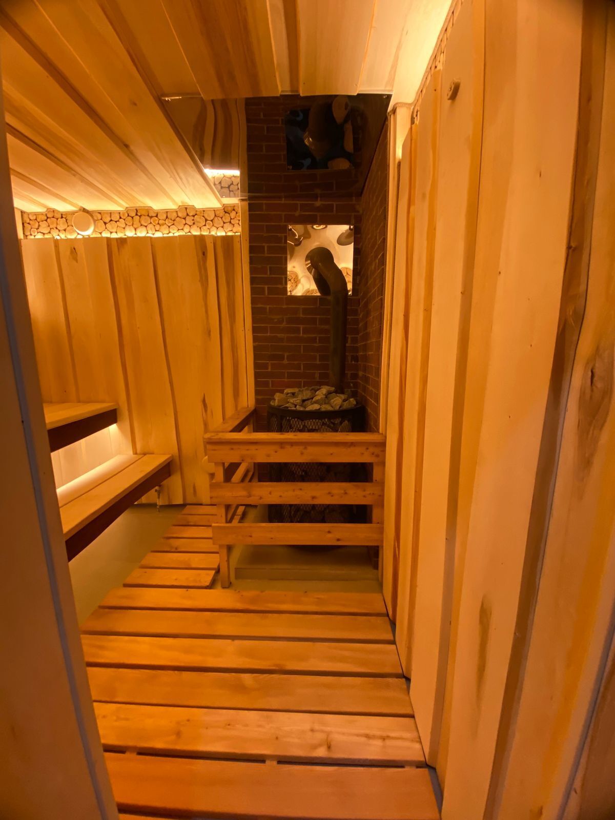 A sauna with wooden benches and a brick wall.