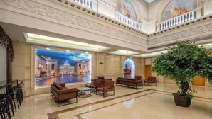 A spacious lobby with a large seating area, a potted plant, and a mural of a cityscape.