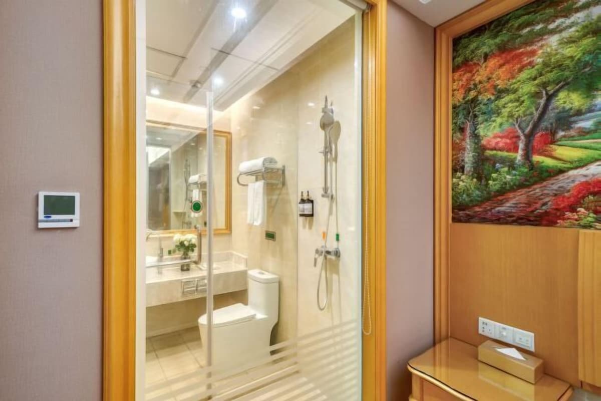 A modern bathroom with a glass shower enclosure, a toilet, and a sink.