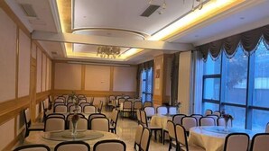 A conference room with round tables and chairs, large windows, and a chandelier.