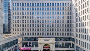 A multi-story hotel with a central entrance, large windows, and a modern architectural design.
