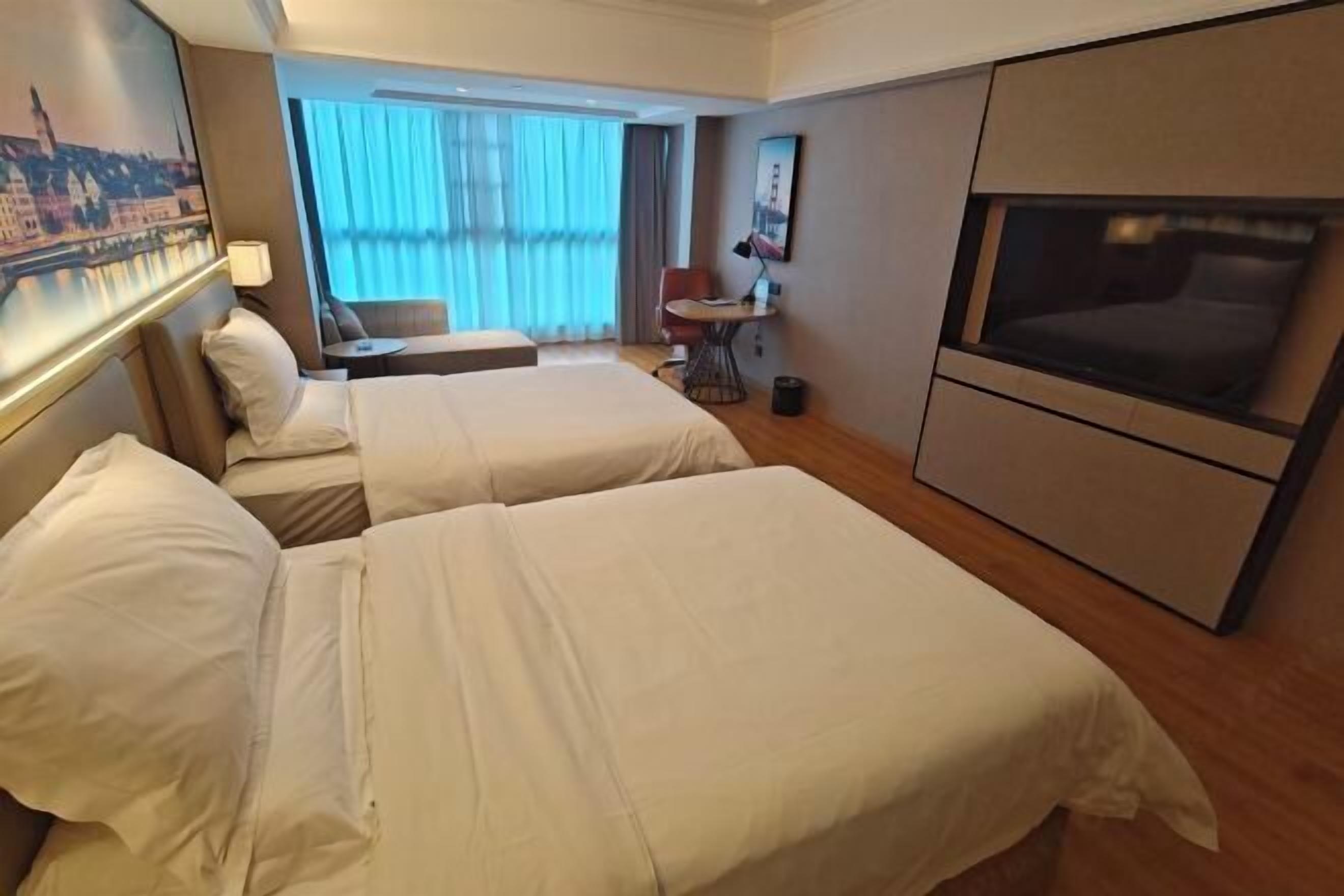 Una habitación de hotel con dos camas, un televisor, un escritorio y una silla.