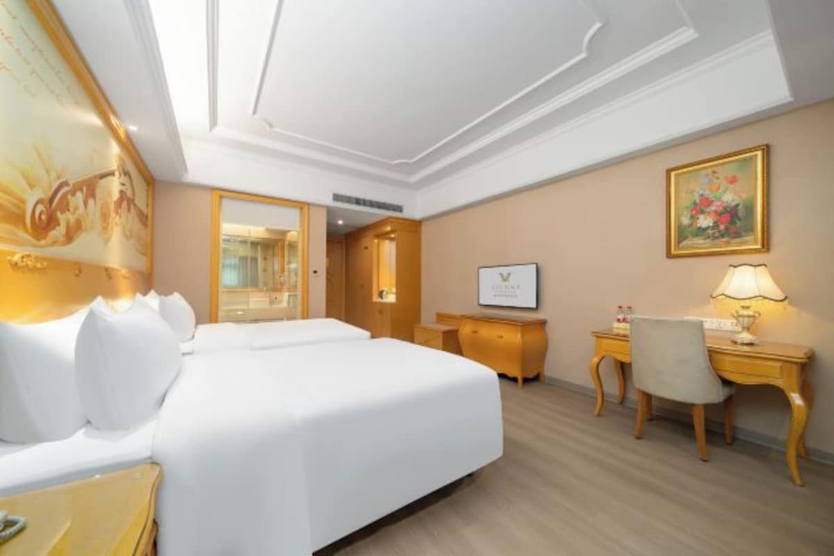 Ein Hotelzimmer mit einem großen Bett, einem Schreibtisch, einem Stuhl und einem Gemälde an der Wand.