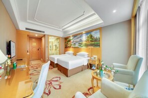 A hotel room with two beds, a desk, a chair, a small table, and a painting on the wall. - Vienna International Hotel (Hangzhou Weilai Science City) (Hangzhou)