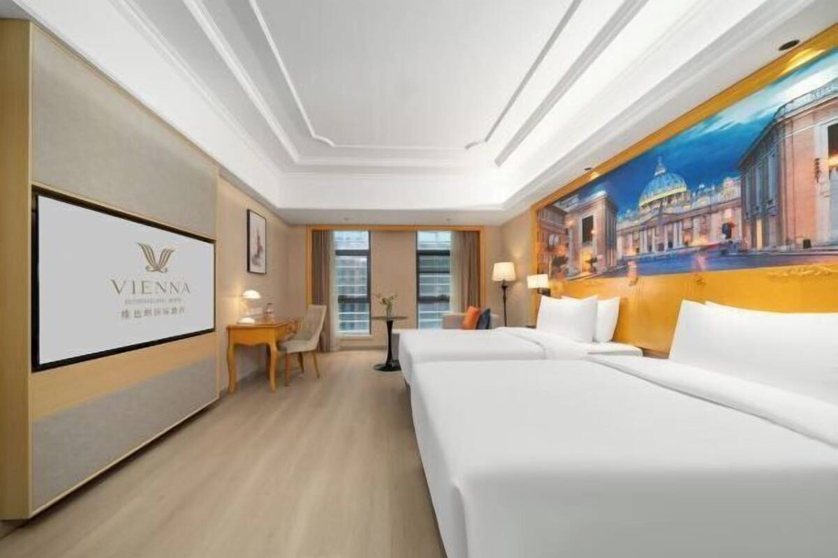 Una habitación de hotel con dos camas, un escritorio, una silla y un cuadro en la pared.