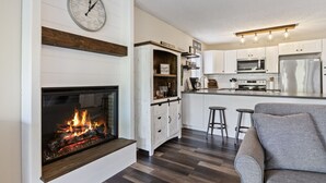 Een moderne keuken met witte kasten, een ingebouwde magnetron en een roestvrijstalen koelkast.
