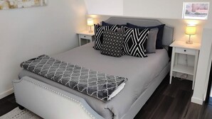 A neatly arranged bedroom with a bed, two bedside tables, and a wall-mounted artwork. - Cozy, Quaint and Sophisticated Loft Style Tiny Home!  (Flagstaff)