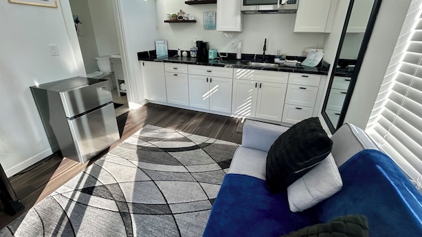 A compact kitchen with white cabinets, a built-in microwave, and a stainless steel refrigerator. - Cozy, Quaint and Sophisticated Loft Style Tiny Home!  (Flagstaff)