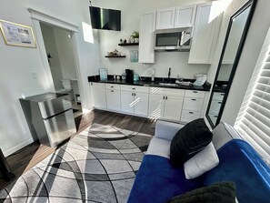 A compact kitchen with white cabinets, a built-in microwave, and a stainless steel refrigerator. - Cozy, Quaint and Sophisticated Loft Style Tiny Home!  (Flagstaff)