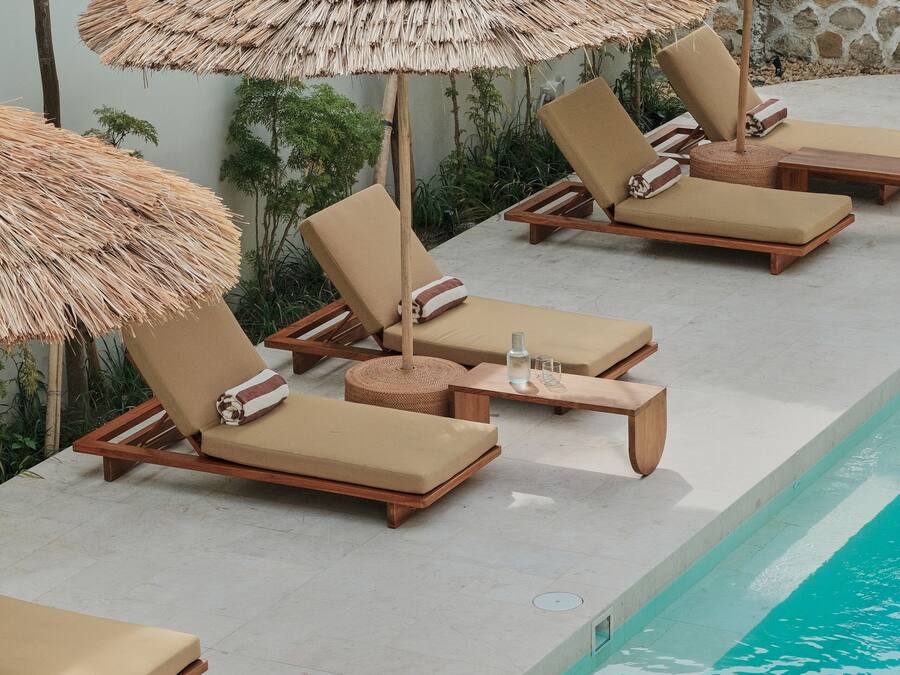 A poolside area with lounge chairs and thatched umbrellas.
