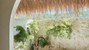 Une salle de bain moderne avec une grande baignoire, un petit tabouret en bois et un mur en pierre agrémenté de plantes.