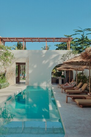 Un área de piscina con sillas de descanso y una pérgola.