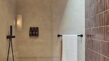 Ein modernes Badezimmer mit einer gläsernen Duschkabine, einem hölzernen Hocker und einem Handtuchhalter.