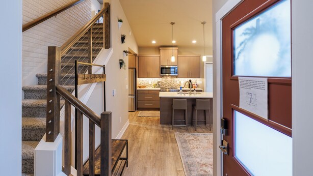 Una cocina moderna con una isla central, electrodomésticos de acero inoxidable y una escalera de madera.