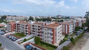 A residential building with multiple floors, balconies, and a parking area.