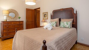A neatly arranged bedroom with a wooden bed, a dresser, and a mirror.