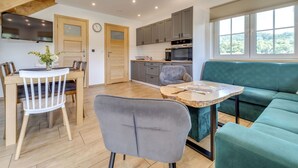 A modern kitchen with grey cabinets, a built-in oven, and a dining area with a wooden table and chairs.