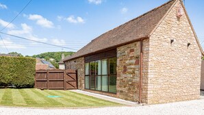 A stone building with a tiled roof, large windows, and a wooden fence. - The Barn in Longhope - Luxury Barn Conversion (Longhope)