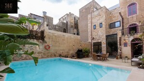 A swimming pool with stone buildings in the background. - Ultimate luxury home experience in beautiful Rabat (Ir-Rabat)