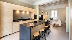 A modern kitchen with a central island, bar stools, and a dining area with a sofa and a coffee table. - Ultimate luxury home experience in beautiful Rabat (Ir-Rabat)