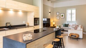 A modern kitchen with a central island, a dining area with stools, a sofa, and a TV. - Ultimate luxury home experience in beautiful Rabat (Ir-Rabat)