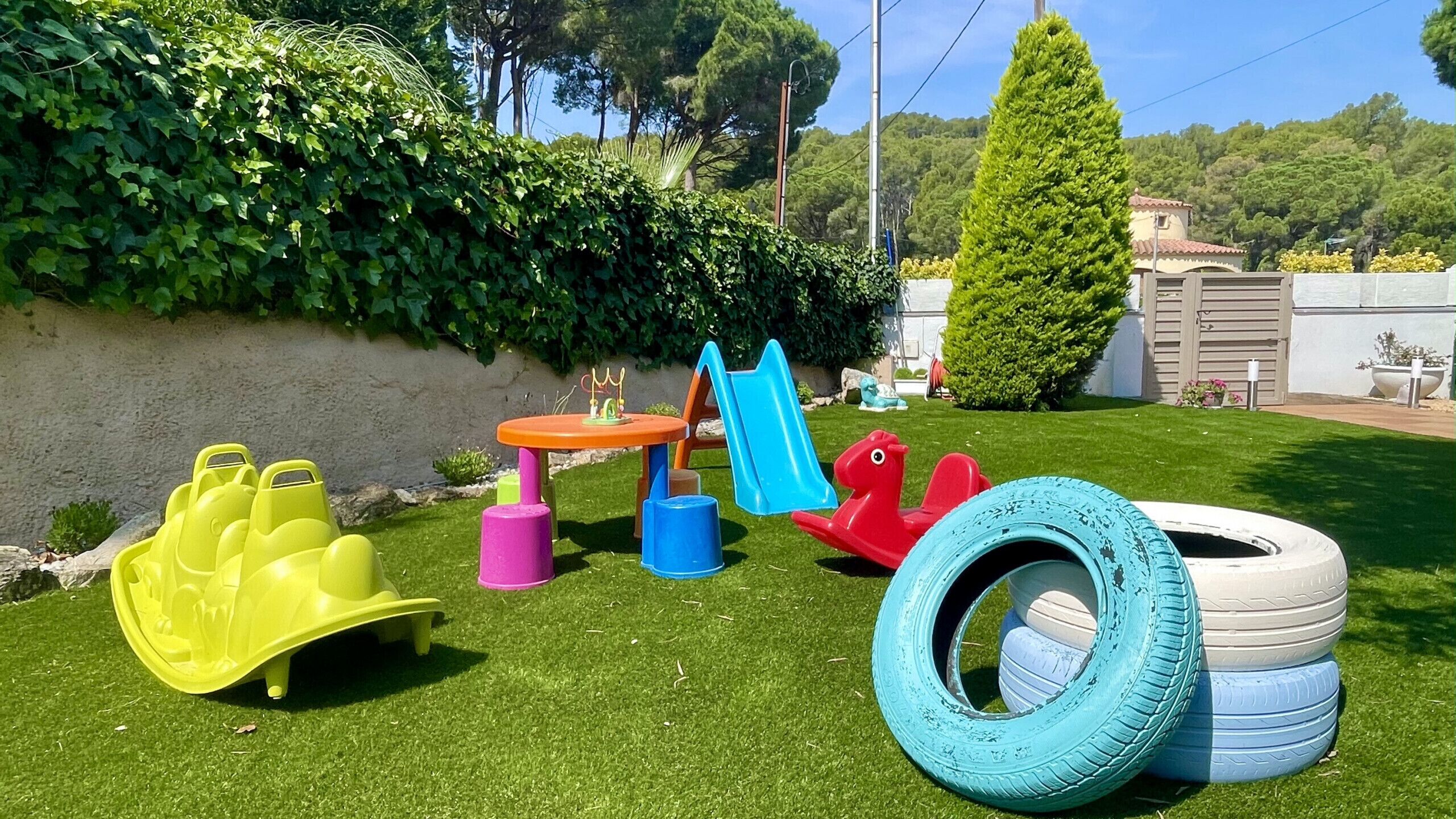 A grassy outdoor area with a slide, a small table, and a tire swing.