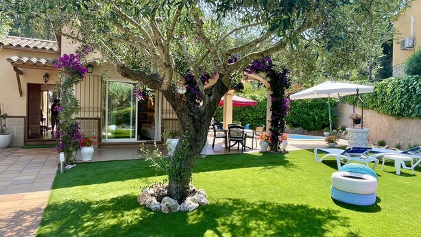 Un jardin bien entretenu, agrémenté d’un arbre, d’un espace salon extérieur et d’une piscine.