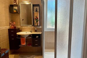 Une salle de bain avec un lavabo, un miroir et une fenêtre embuée.
