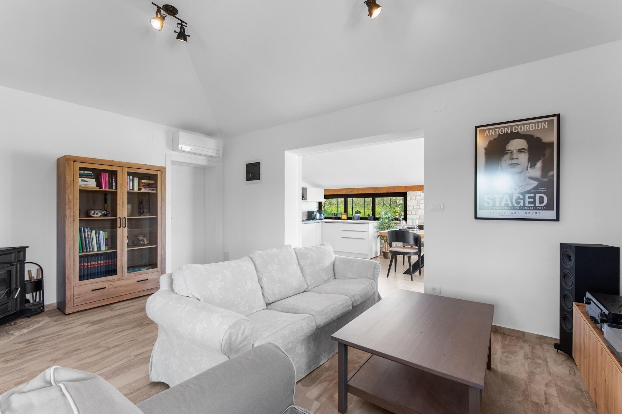 Una sala de estar moderna con un sofá, una mesa de centro, un mueble de madera y un cartel en la pared.