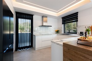 A modern kitchen with white cabinetry, a marble countertop, and a built-in stove.