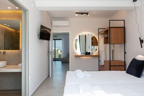 A modern hotel room with a large bed, a built-in TV, a mirror, and a view of the outdoors.
