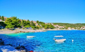 A coastal town with clear blue waters, boats, and buildings on the hillside.