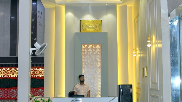 A reception area with a marble reception desk, a person seated behind it, and a modern ceiling design. - Hotel Aalishan Garden (Bareilly)