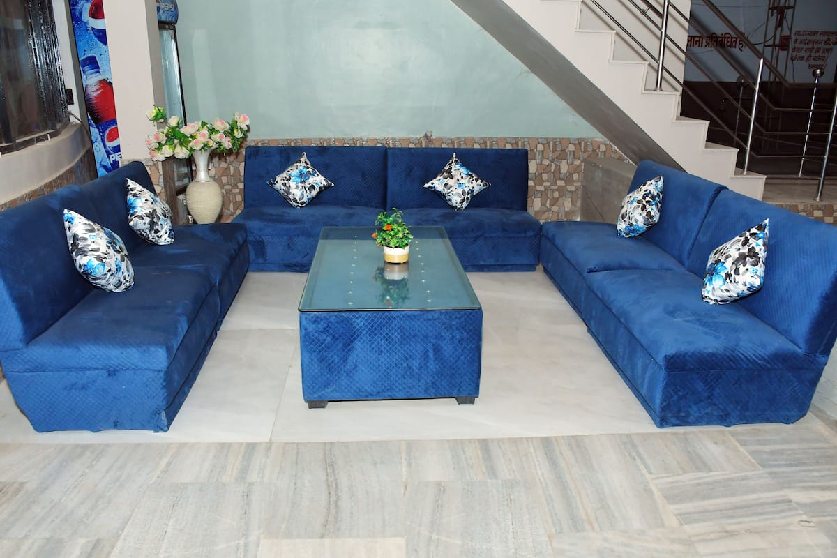 Un ensemble de canapés modulaires bleus agrémenté de coussins à motifs, une table basse en verre avec une plante, et un mur d’accent en pierre.