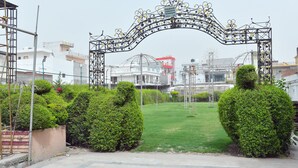 An entrance gate with a decorative arch, a well-maintained lawn, and neatly trimmed bushes. - Hotel Aalishan Garden (Bareilly)