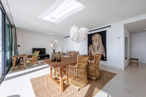 A modern dining area with a wooden table, wicker chairs, and a large vase of flowers. - New apartment with 2 bedrooms and a 50m2 terrace. (Fuengirola)