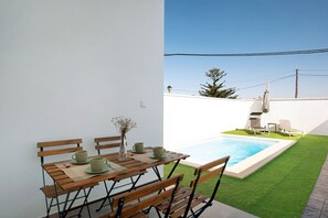 A patio with a pool, wooden furniture, and a white wall. - Holiday Apartment "Casa Lavanda" with Private Pool, 2 Private Terraces & A/C (Vejer de la frontera-Cadiz)