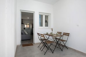 Ein Essbereich mit Tisch und Stühlen, einem Fenster und Blick in ein Wohnzimmer.