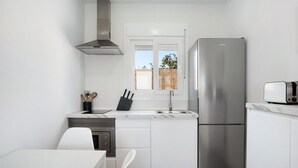 Een moderne keuken met witte kasten, een roestvrijstalen koelkast, een inbouwoven en een raam met uitzicht.