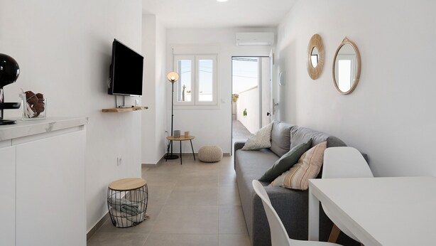 Een moderne woonkamer met een bank, een televisie, een ronde tafel en een klein krukje.
