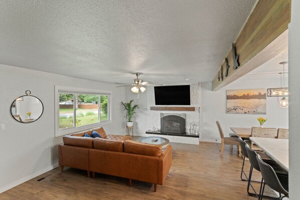 Una sala de estar con sofá, chimenea, televisor y un comedor con sillas y mesa.