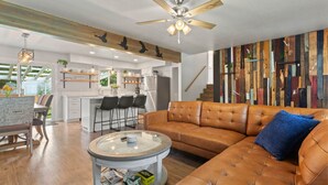 Ein modernes Wohnzimmer mit einer Ledersofa, einem runden Couchtisch und einem Deckenventilator.