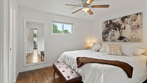 Ein Schlafzimmer mit einem großen Bett, einem Deckenventilator, einem Fenster und einem Bild an der Wand.