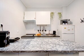 A kitchen with white cabinets, a microwave, a refrigerator, and a sink. - Apartment "Barrinha Beach" with Sea View, Shared Terrace & Wi-Fi (Esmoriz)