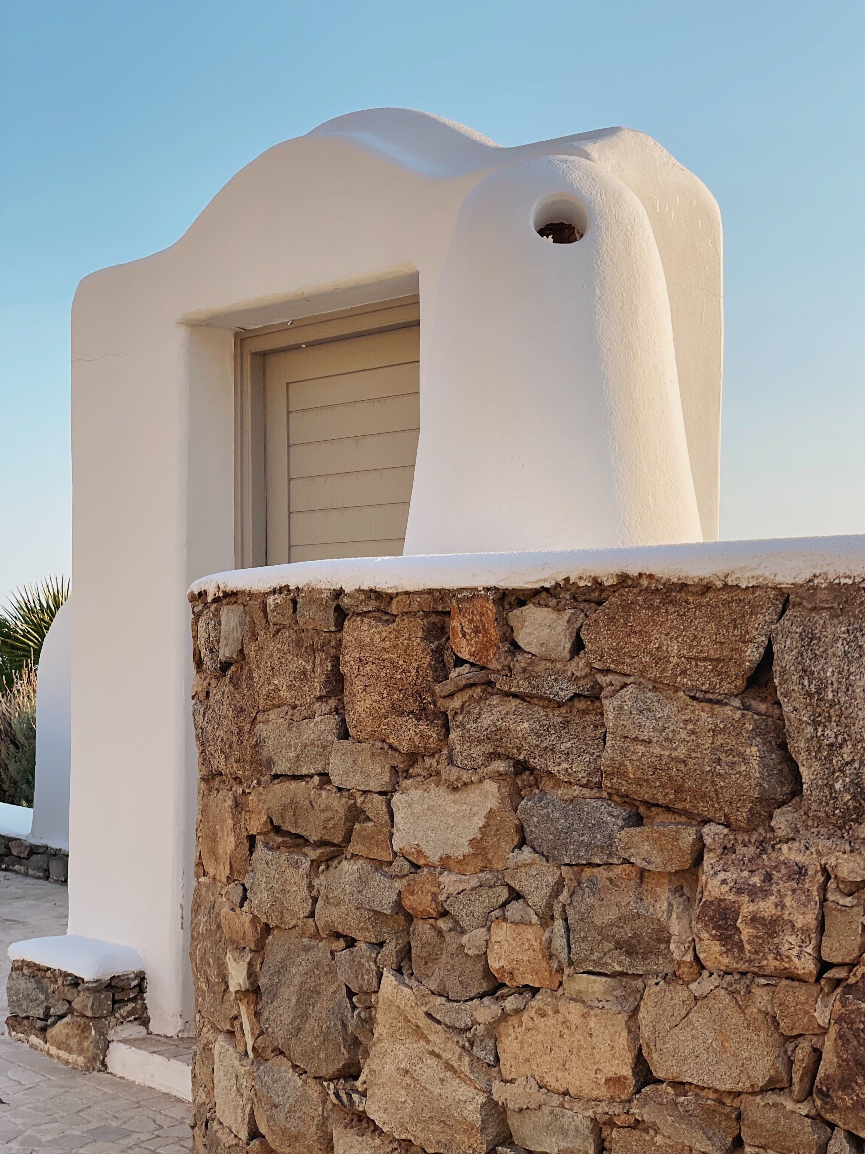 Un edificio con pared de piedra y puerta color beige.