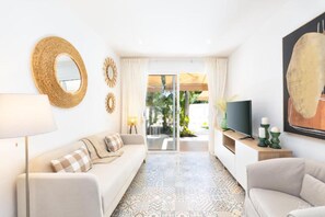 A modern living room with a sofa, a TV, and a patterned rug.