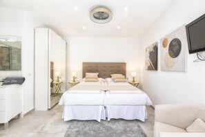 Une chambre d’hôtel avec un grand lit, des tables de chevet, une télévision et un miroir.