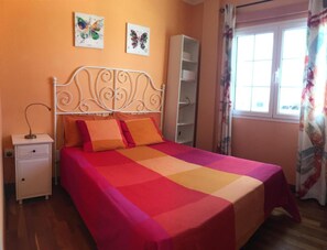 Une chambre à coucher comprenant un lit, une table de chevet, une armoire et deux œuvres d’art murales représentant des papillons.
